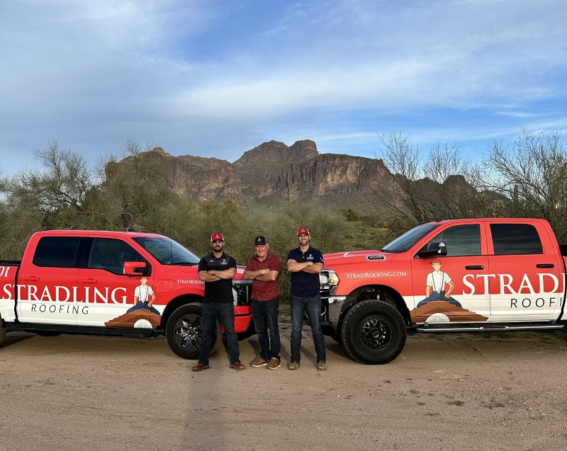 STRAD Roofing team standing with service trucks in Phoenix before a roof inspection
